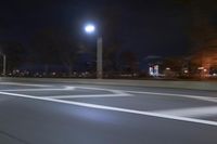 a truck is driving down a highway with lights shining on it at night behind him are a street lamp