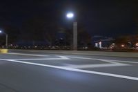 a truck is driving down a highway with lights shining on it at night behind him are a street lamp