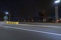 a truck is driving down a highway with lights shining on it at night behind him are a street lamp