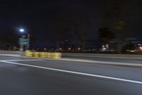 a truck is driving down a highway with lights shining on it at night behind him are a street lamp