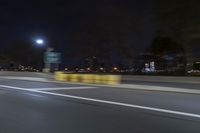 a truck is driving down a highway with lights shining on it at night behind him are a street lamp