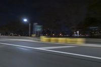 a truck is driving down a highway with lights shining on it at night behind him are a street lamp