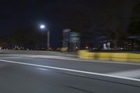 a truck is driving down a highway with lights shining on it at night behind him are a street lamp
