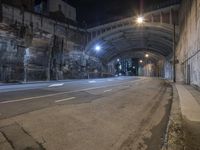 a view of an empty highway under an arched bridge at night time during the day