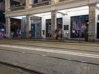 the light rail at night on the street is illuminated by some lights in front of the building