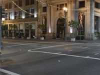 city street at night with several pedestrians crossing street signs and buildings behind it in the background