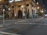 city street at night with several pedestrians crossing street signs and buildings behind it in the background