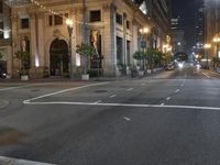 city street at night with several pedestrians crossing street signs and buildings behind it in the background