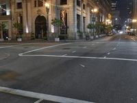 city street at night with several pedestrians crossing street signs and buildings behind it in the background