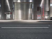 an empty street with a metallic door at night with white lines in the road on both sides