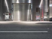 an empty street with a metallic door at night with white lines in the road on both sides