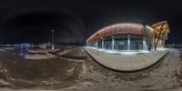 a view from a fisheye lens on an indoor skating rink at night, with a reflection of the building and buildings in the background