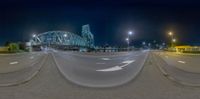 a panorama fisheye photo taken in an industrial area at night, with an orange train going down it