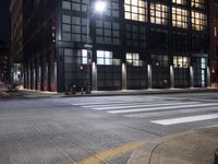 an intersection that has a crosswalk at night in a city at night time with street lights on and buildings near by