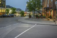 an intersection near a city street filled with cars and lights and a building on either side of the road