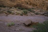 a mountain range near a river with some boulders on it at night time with mountains in the background