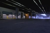 an empty street with many cars driving on it at night, and lights hanging off the side of buildings and overhead