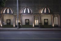 a building with several arched windows and a street lights along the side walk at night