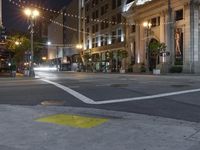 a view of a city street at night with lights on and an open fire hydrant