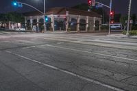 a street at night with a stoplight at a bus stop and a white car stopped at a red light