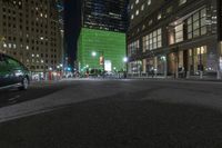 there is a bright green building behind the city buildings at night - - - in this particular area of the street