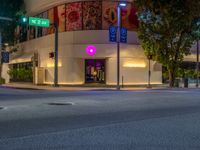 a view of a store front lit up at night by colorful lights on the street