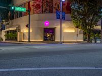 a view of a store front lit up at night by colorful lights on the street