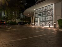 a building lit up at night, with illuminated screens on it's facade and a parking lot in front