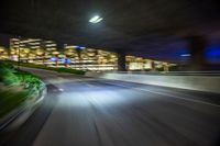 a car is moving fast on the freeway at night time in the city streets of a big city