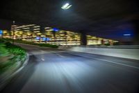 a car is moving fast on the freeway at night time in the city streets of a big city