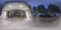 a 360 view mirror shows the street and buildings at night with cars driving through the alley