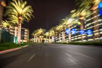 palm trees and buildings at night, blurry picture, seen from a passing vehicle