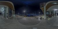 the panoramic view of an empty street at night of a busy city marina with a fire hydrant nearby