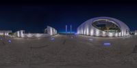 a panorama photo of buildings in the night, lit up by lights, against a dark blue sky