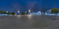 a view from an empty parking lot at night with buildings in the background and lots of light shining