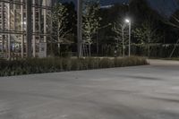 a parking lot with parking lots at night and lights on it at night, and some trees in the background