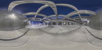 an abstract photo showing an underground parking lot and a long walkway at night time and a train station with lights on