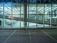 a parking lot near large windows is shown at night time, and has no cars