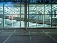 a parking lot near large windows is shown at night time, and has no cars