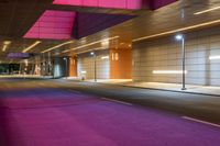 purple and green lights and modern concrete wall in an empty parking space at night,