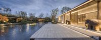 a view of a beautiful pool next to an outdoor living room at night by the house