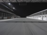 a car is driving down a track by itself in an empty building at night,