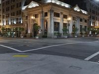 the lights on the street are reflecting off of the buildings at night time as if at an intersection