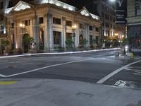 the lights on the street are reflecting off of the buildings at night time as if at an intersection