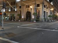 the lights on the street are reflecting off of the buildings at night time as if at an intersection