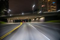 blurry photo taken looking at the road underpass at night time in this city