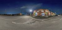 a view of an empty parking lot at night time by some buildings on the street