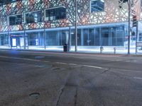 an empty street near a building at night with no traffic lights in the foreground