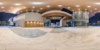 an indoor skate park that includes skating rinks and steps at night time with some people standing inside of the building