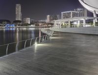 a bridge is lit up at night with light reflecting off the water below it and a tall building on the side